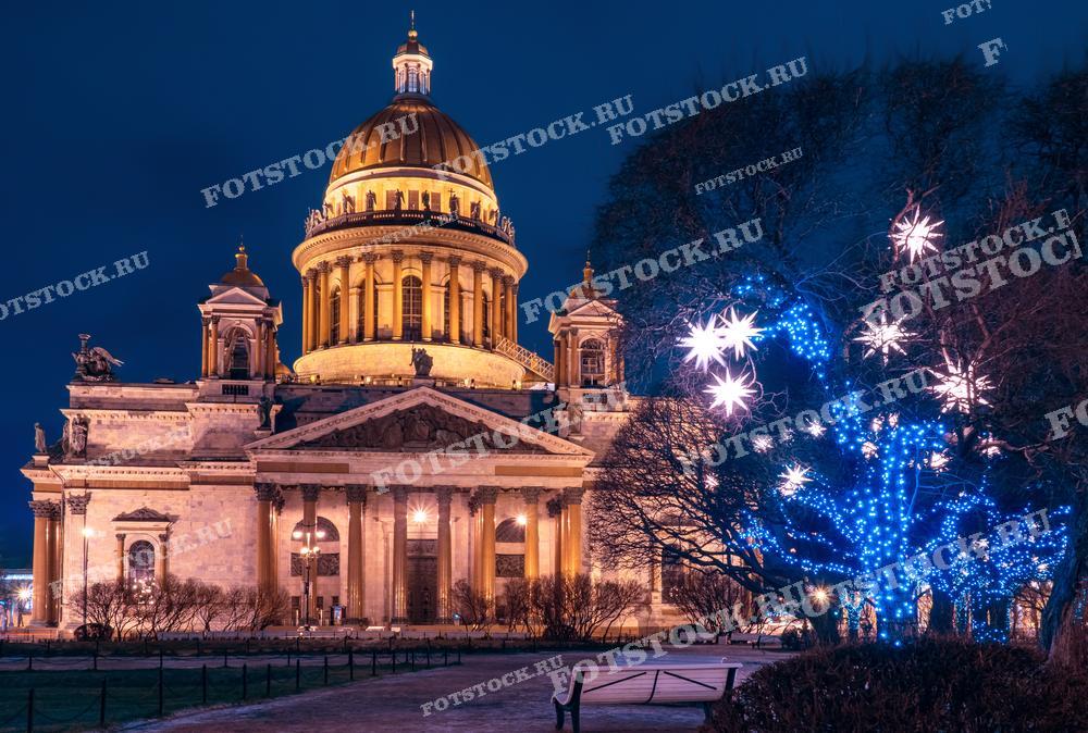 На фотографии изображен Исаакиевский собор в Санкт-Петербурге в рождественский вечер, украшенный праздничными огнями. Это великолепное здание, освещенное ночью, создает волшебную атмосферу праздника. Фото может быть использовано для рождественских открыток, туристических буклетов, веб-сайтов, а также для личных и коммерческих проектов, связанных с культурой и архитектурой Санкт-Петербурга.